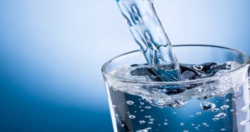 Pouring Water Into Glass On Blue Background