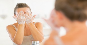 Young woman washing face in bathroom